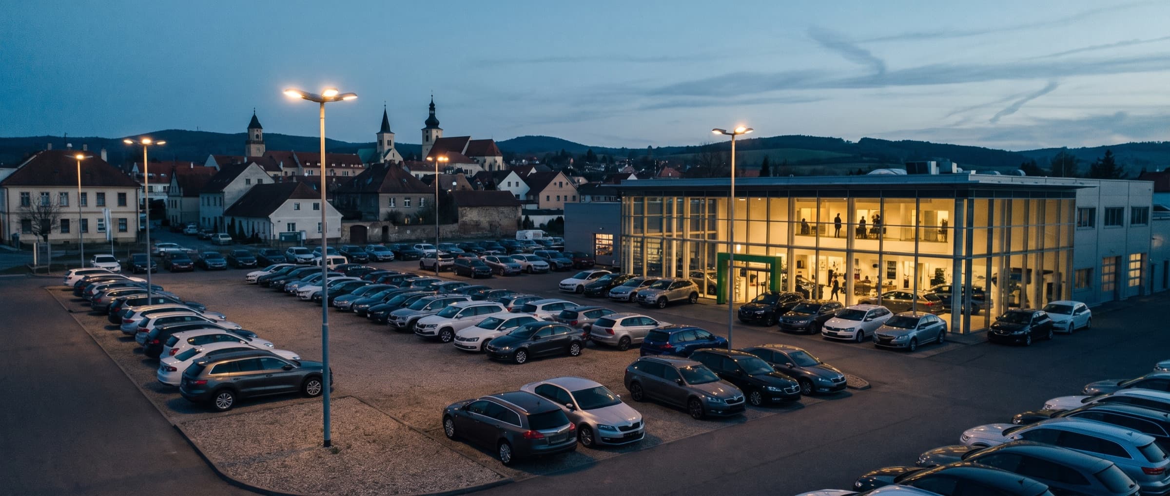 Cars lined up on a dealership forecourt at dusk