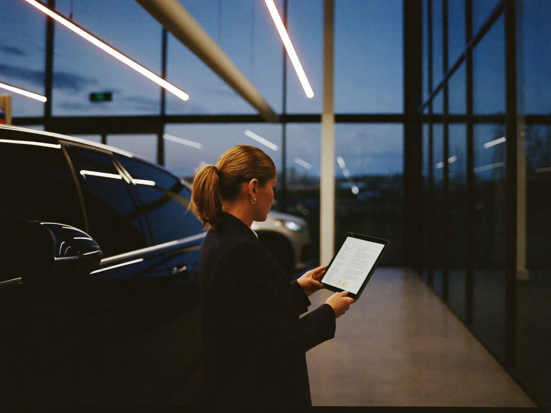 A salesperson reviewing notes on a tablet beside a prepared SUV in the showroom