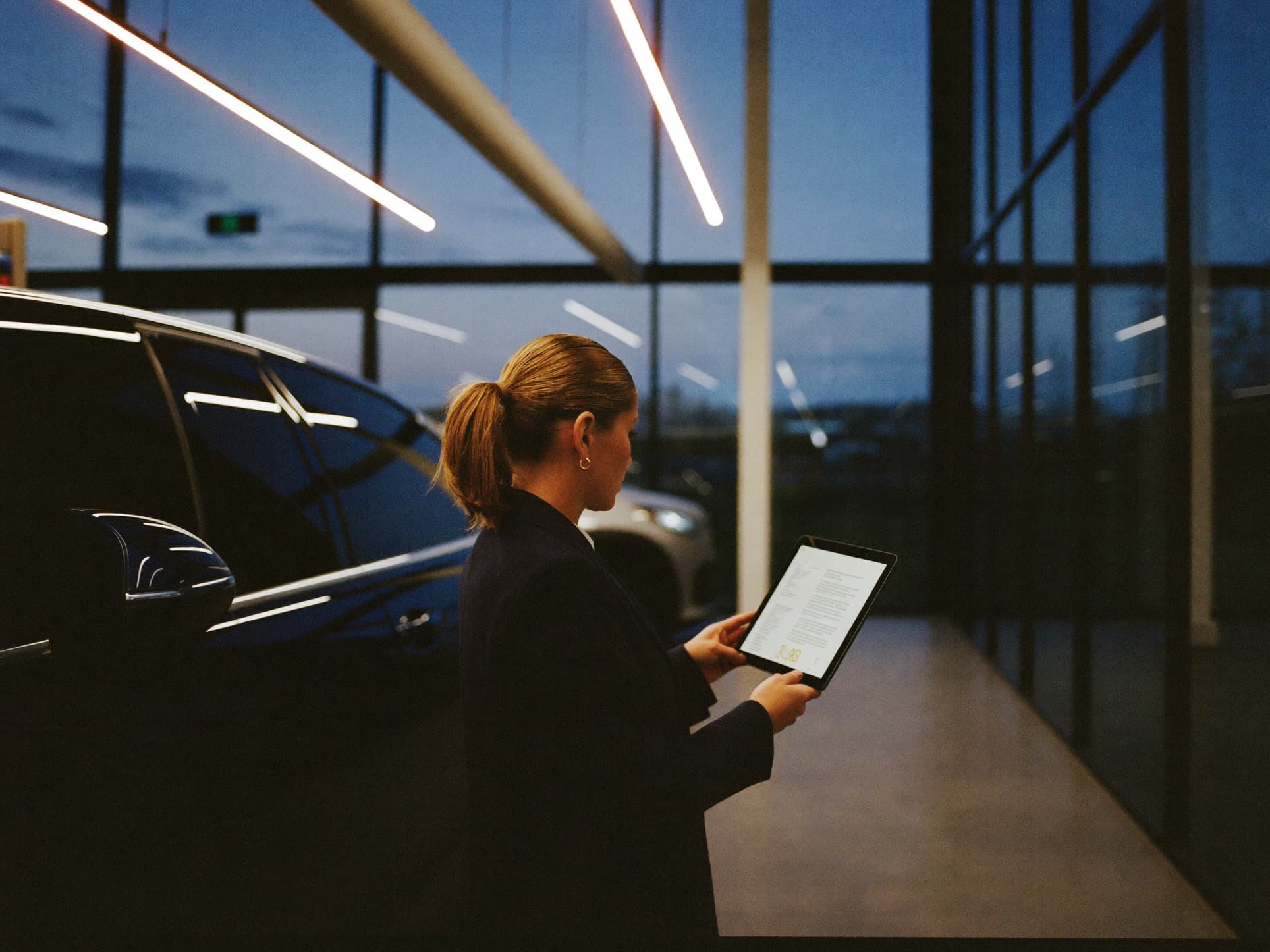 A salesperson reviewing notes on a tablet beside a prepared SUV in the showroom