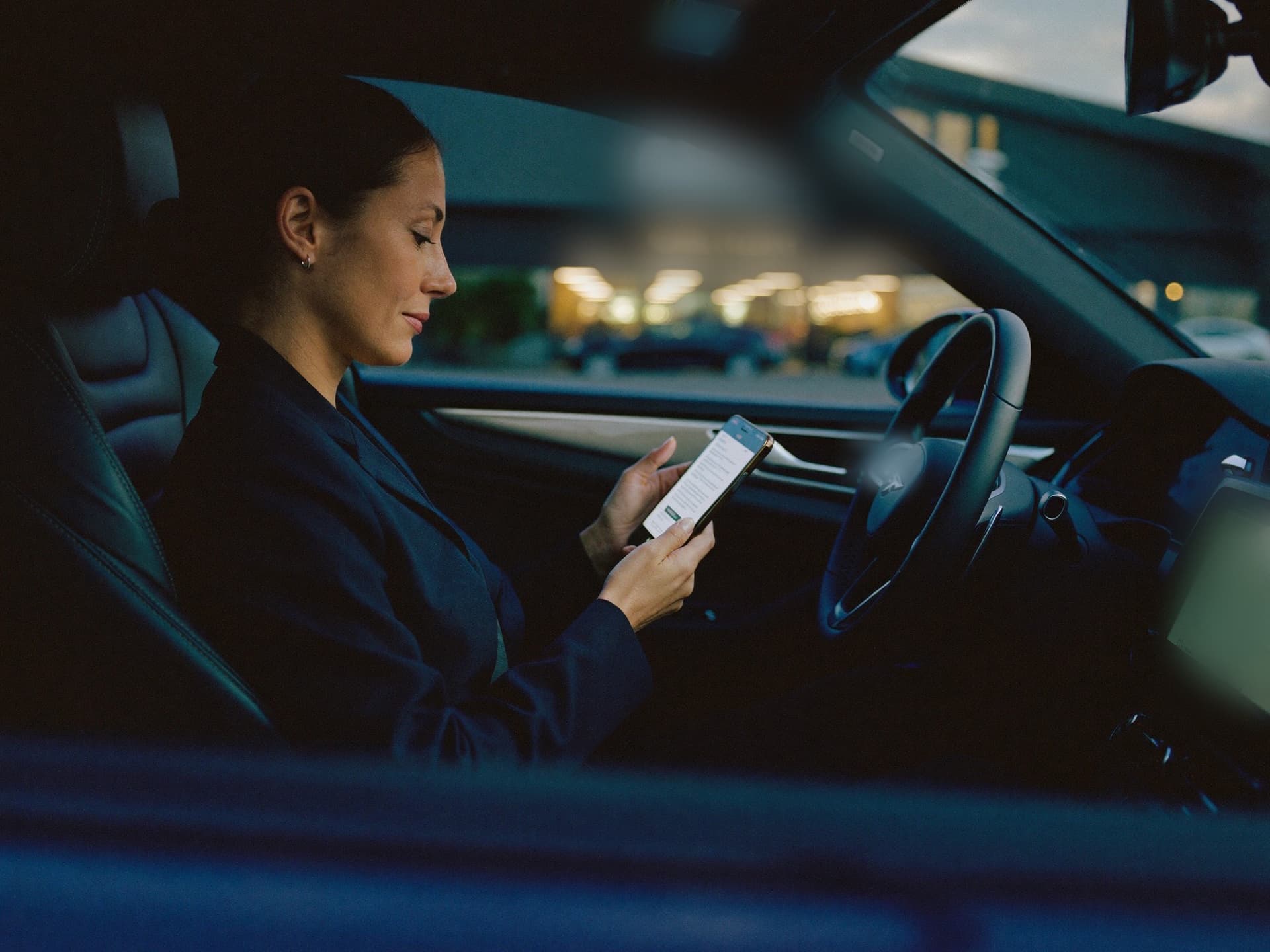 Car buyer reading a dealership reply on her phone in the evening